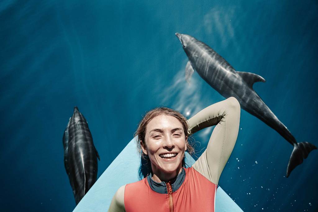 Smiling guest watching dolphins alongside a panga boat near La Ventana